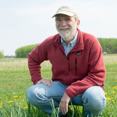 Phil Robertson kneeling in a prairie field