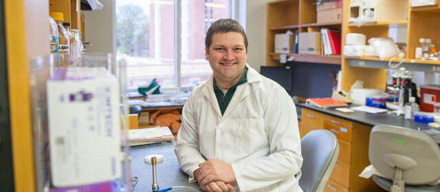 Man in lab coat sitting at his work station