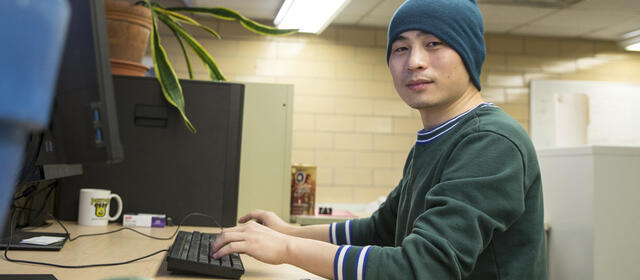 Postdoctoral researcher Xanhua Xie sits in front of a computer at the Wisconsin Energy Institute in Madison, Wis.
