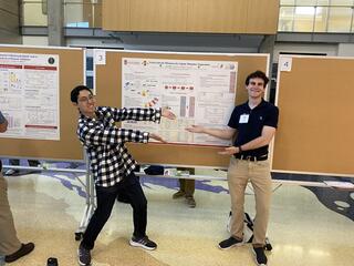Two boys gesture towards a scientific poster