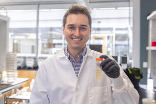 Man in white lab coat holding test tube
