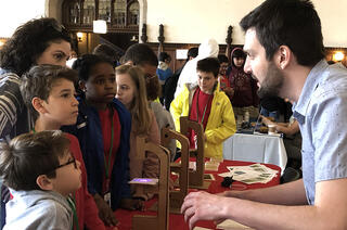 François Alberge talks to a group of kids and adults gathered around a table.