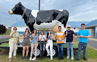 Group of students from the GLBRC 2022 Summer Undergraduate Research Program standing in front of a fiberglass cow