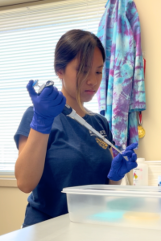 Janice Tran is pipetting into a tube at a lab bench.