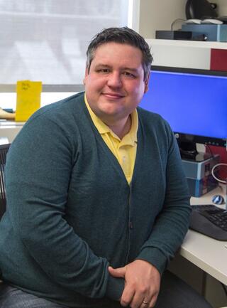 Kevin Myers sitting at an office desk with a monitor visible behind him.