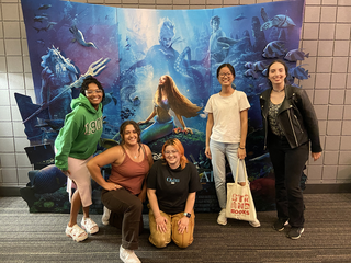 Stephanie Qu and other REU students stand in front of a movie poster