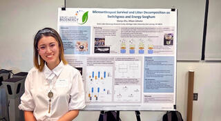 Qianyu Zhu stands to the left of her research poster