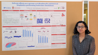 Taskina Zaman Jui stands next to her research poster