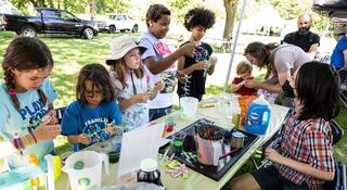 Several children standing at a table with small components of a science experiment