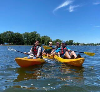 The 2022 GLBRC Summer Undergraduate Research Program participants pose for a picture while kayaking on Lake Lansing. 