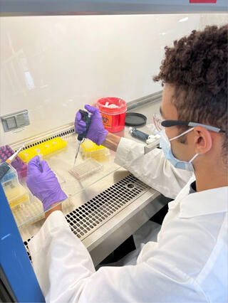 Tai Brass pipetting samples in a fume hod.