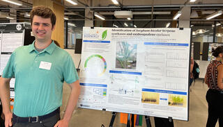 Tyler Criss stands to the left of his research poster.