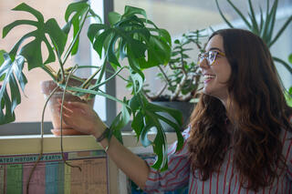Brunette woman smiles at plants.