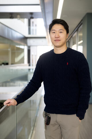 Man in black shirt and tan pants standing in brightly lit atrium