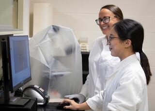 Two women standing in front of lab equipment